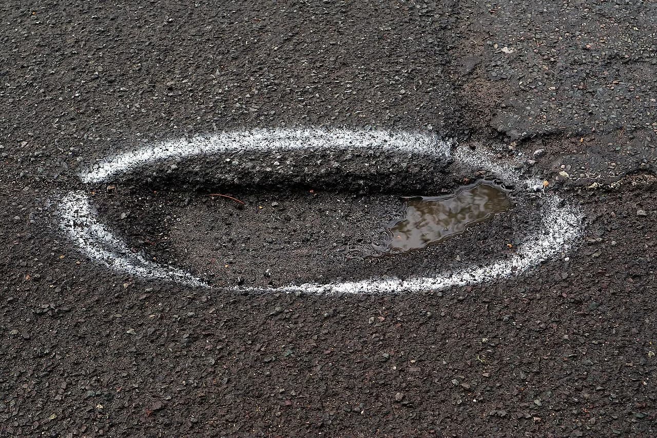 A pothole on a UK road outlined in white paint for repair